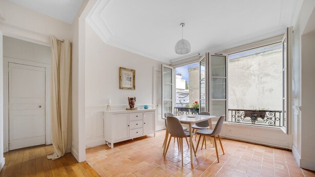 A room with a dining table and chairs, a white cabinet, a picture frame, and a large window with a view of buildings. - République Of City Paris (Paris)