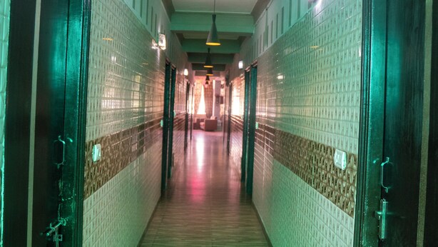 A corridor with tiled walls, wooden flooring, and doors on both sides. - Hotel Ved & Restaurant  (Agra)