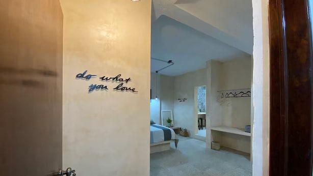A room with a bed, a desk, and a wall with a motivational quote.