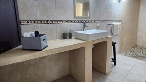 A bathroom with a beige countertop, a white sink, a mirror, and a tiled floor.