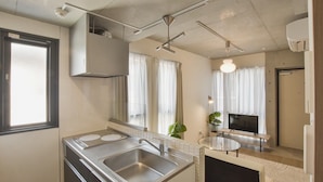 Una cocina moderna con un lavamanos, estufa y comedor con televisor.