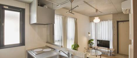 A modern kitchen with a sink, stove, and a dining area with a TV.