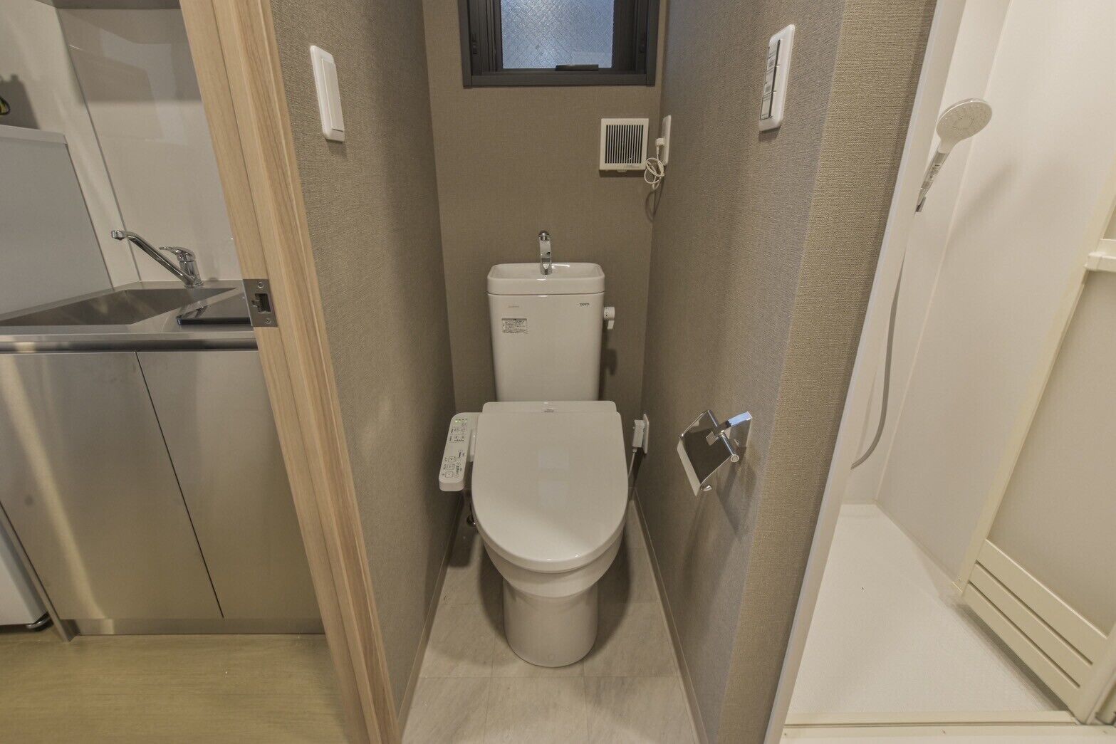Une petite salle de bain comprenant des toilettes, une petite fenêtre et un espace douche.