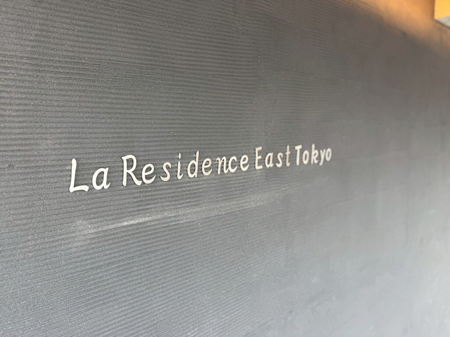 Pared con textura y el texto "La Residence East Tokyo", que indica el nombre del hotel.