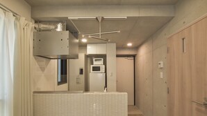 Un pasillo estrecho con pared de azulejos, microondas y puerta de madera.