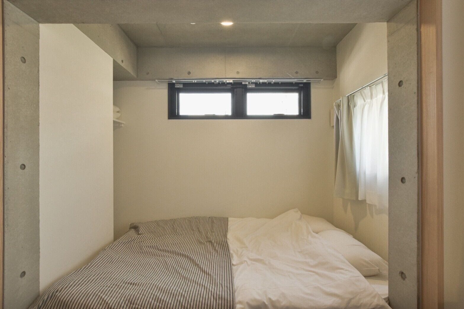 A small, single-bed room with a window and a curtain.