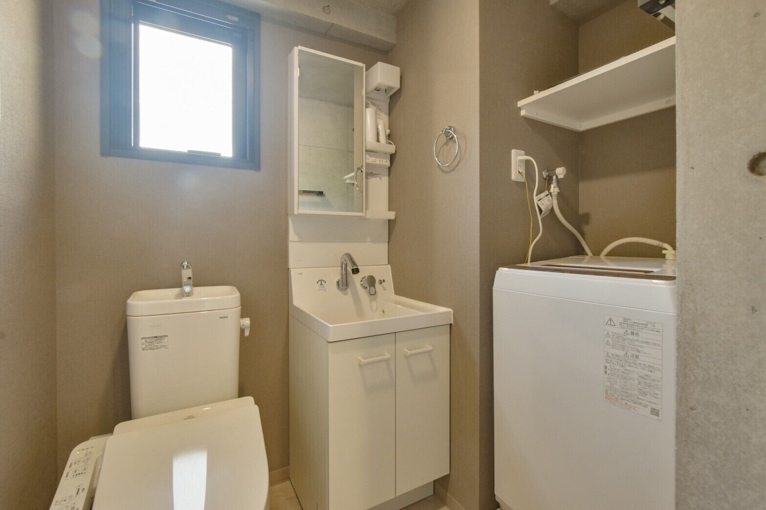 Un bagno piccolo ma funzionale, con il water, il lavandino e una lavatrice.