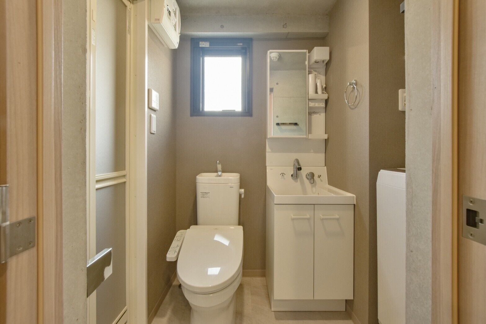 A compact bathroom with a toilet, sink, and a small window.