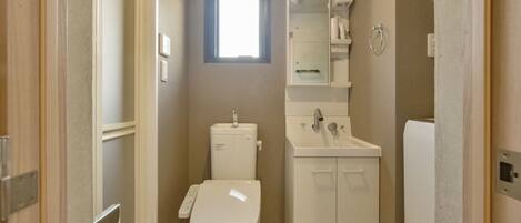 A compact bathroom with a toilet, sink, and a small window.