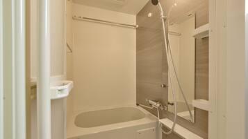 A modern bathroom with a bathtub, shower, and a glass shower enclosure.