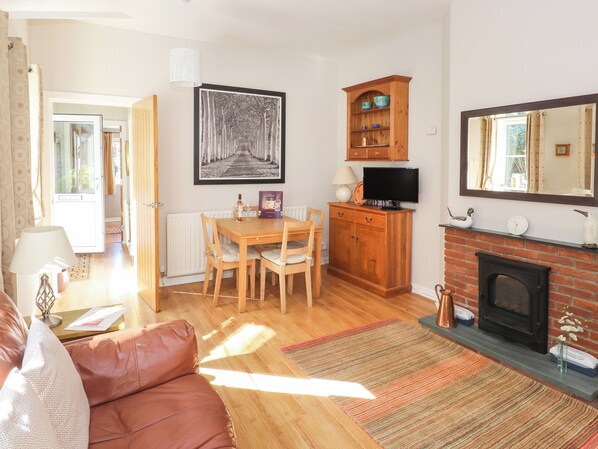 A cozy living room with a fireplace, a dining area, and a TV.