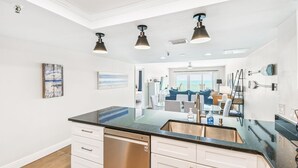A modern kitchen with a large island, built-in dishwasher, and pendant lighting.