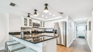 A modern kitchen with a central island, stainless steel appliances, and bar stools.