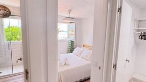 Un dormitorio con cama, ventana y ventilador de techo.
