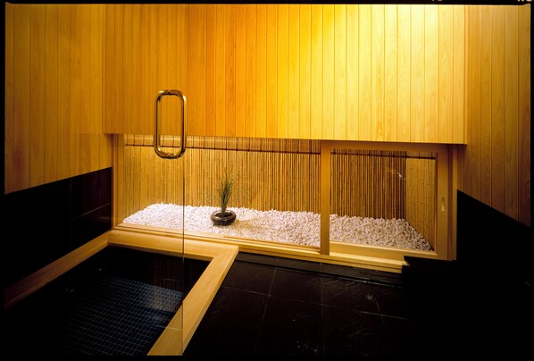 Una sauna con paredes de madera, suelo de baldosas y una planta pequeña en el centro.