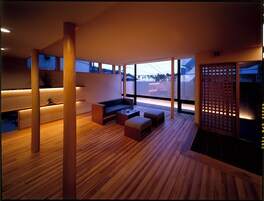 A modern interior with a wooden floor, a sofa, a coffee table, and a view through large windows.