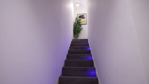 A narrow staircase with dark wooden steps and purple lighting. - Market Street 61A (Watford)