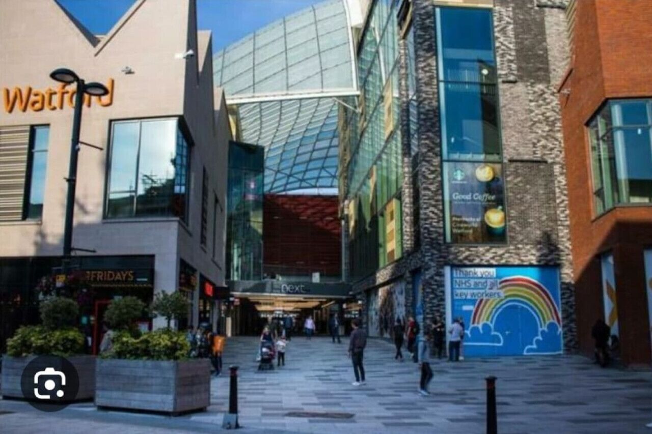 A shopping area with a modern building featuring large glass windows and a stone facade.