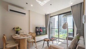 Una sala de estar moderna con comedor, televisor de pantalla plana y un ventanal con vista a la ciudad.