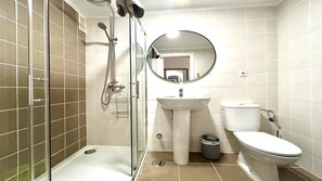 A modern bathroom with a glass shower enclosure, a sink, a toilet, and a mirror.
