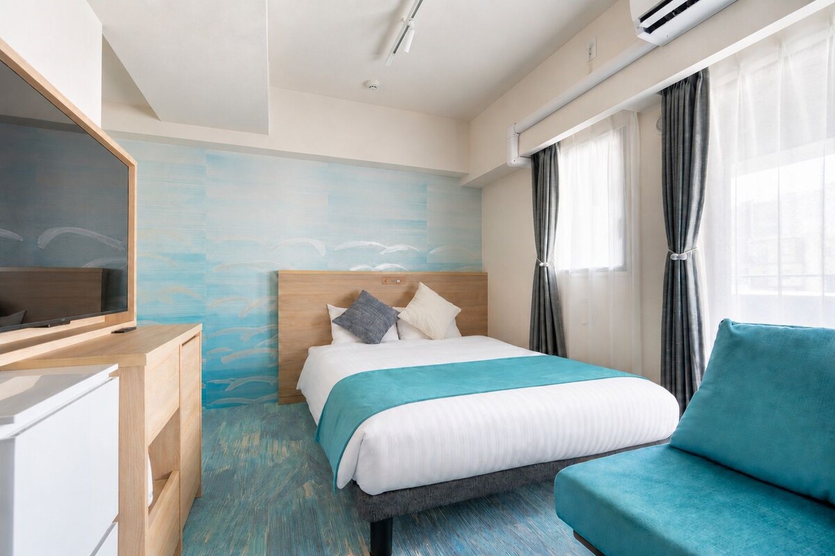 Une chambre d’hôtel avec un lit, une télévision, un bureau et une fenêtre avec des rideaux.