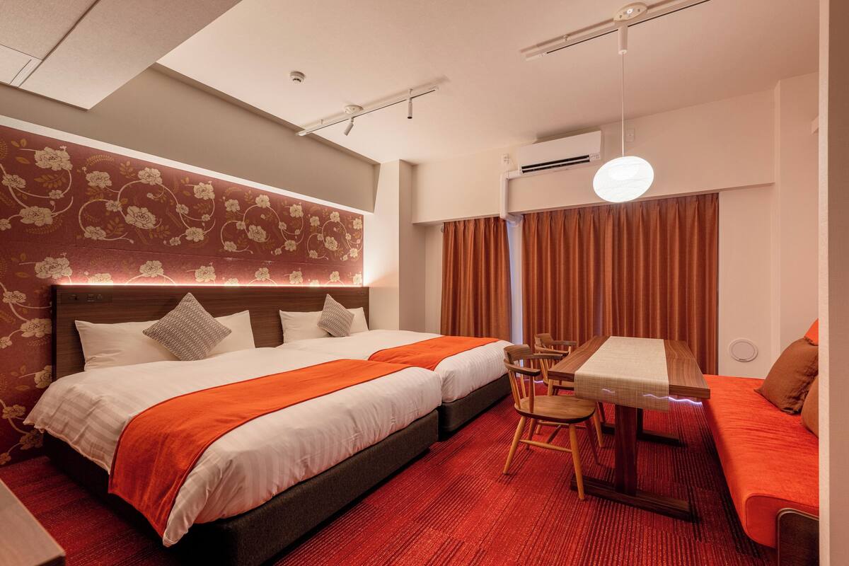Habitación de hotel con dos camas, un escritorio y un sofá.