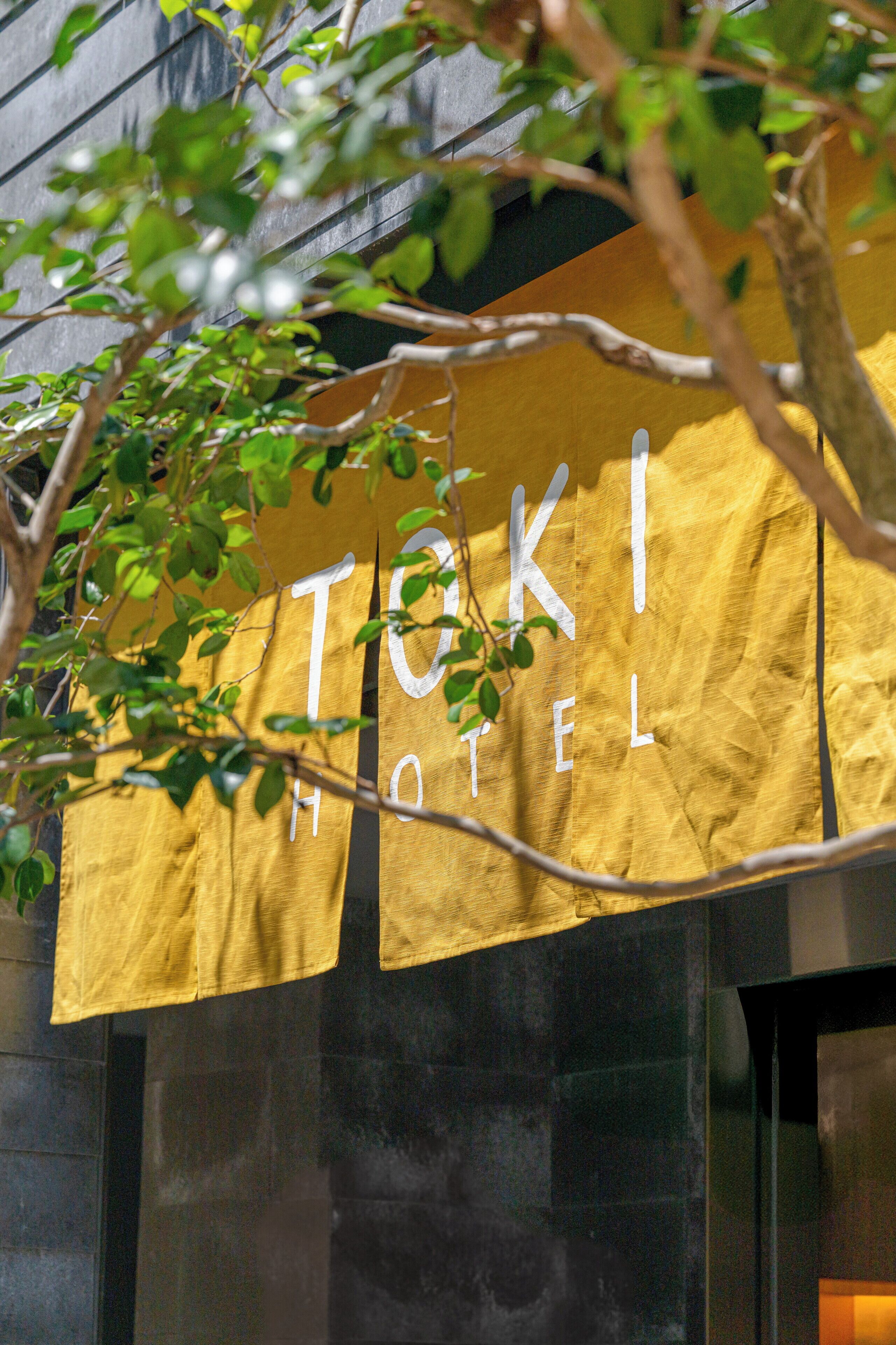 A yellow sign with the text "TOKI HOTEL" partially obscured by foliage.