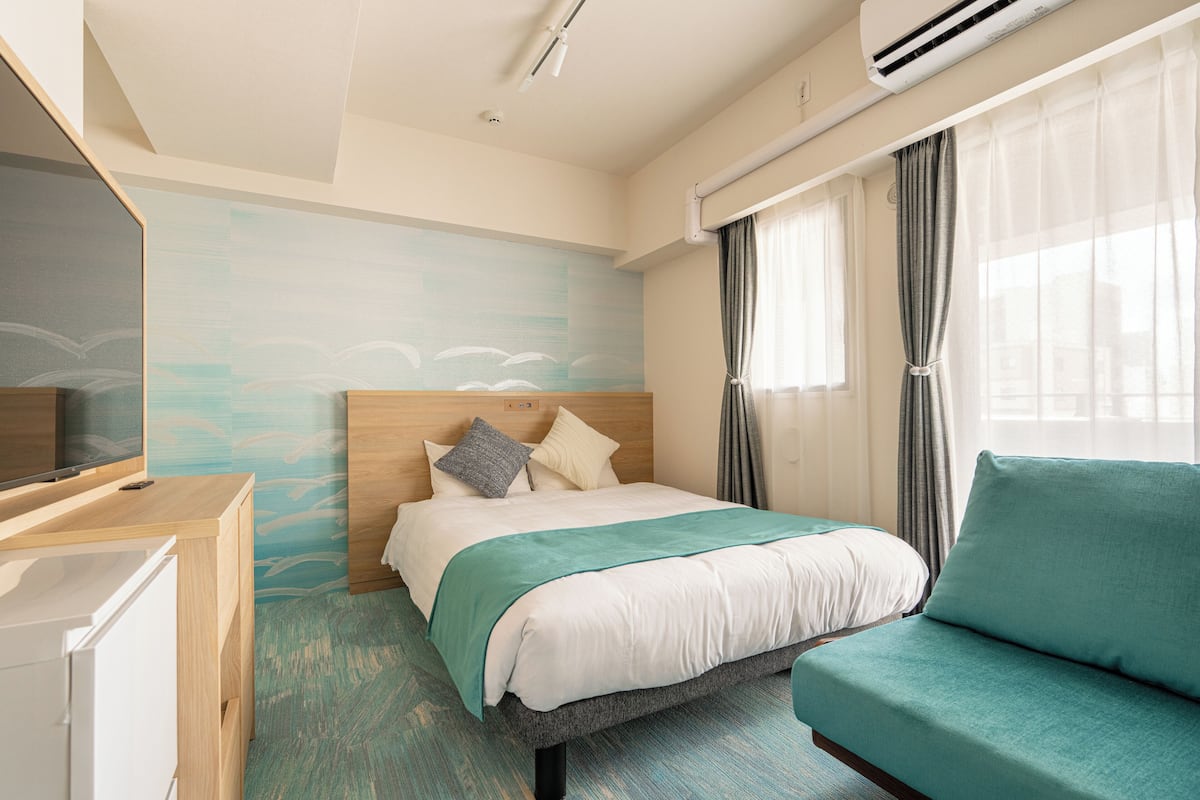 Una habitación de hotel con cama, sofá, televisión y escritorio.
