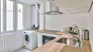 Une cuisine compacte équipée d’un lave-linge, d’un lave-vaisselle et d’un évier.