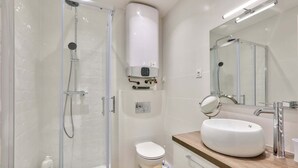 A modern bathroom with a glass-enclosed shower, a white toilet, and a large sink with a mirror. - Paris 2nd: Studio Near Metro, High-Speed WiFi (Paris)