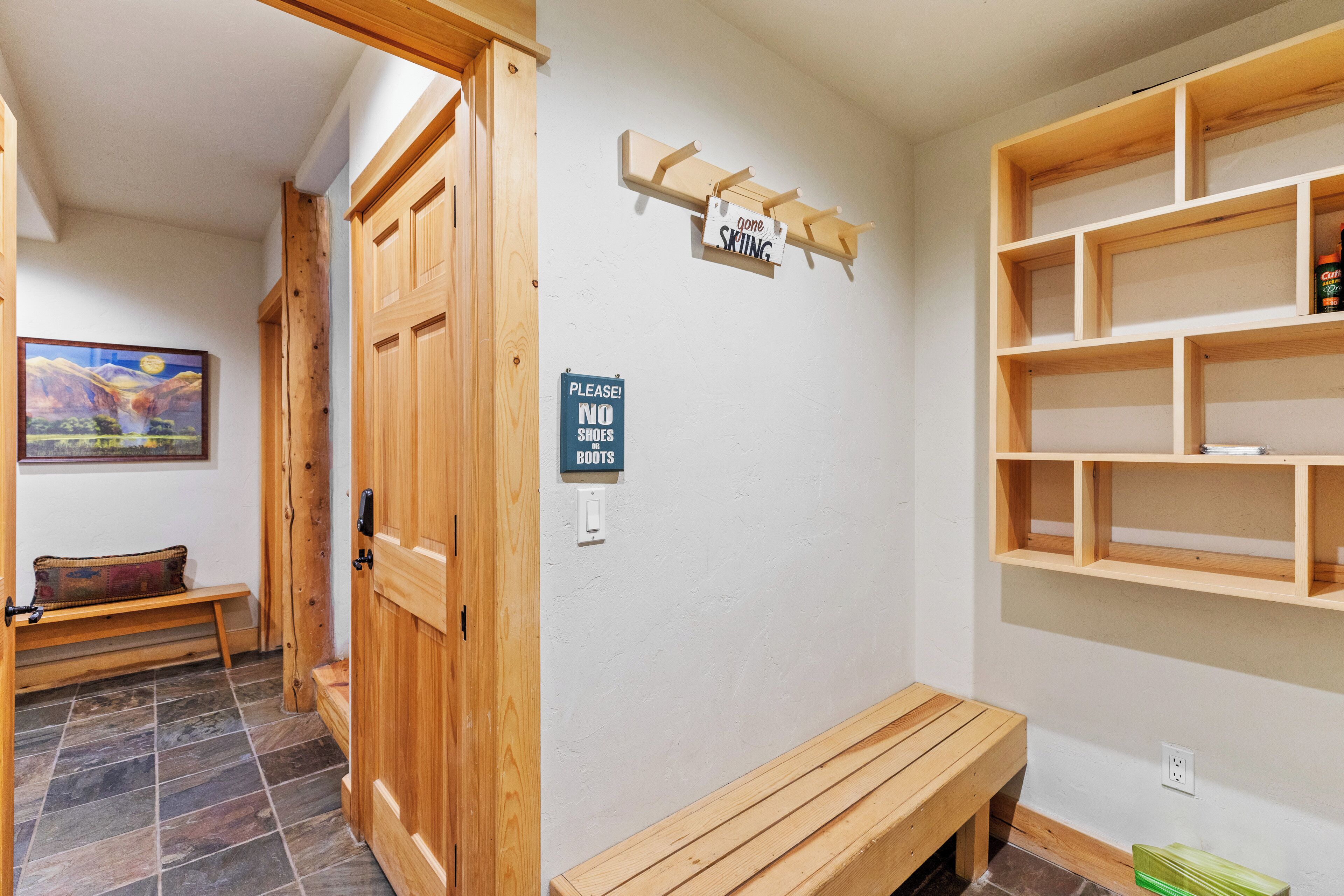 A hallway with wooden doors, a bench, and a sign indicating no shoes allowed.