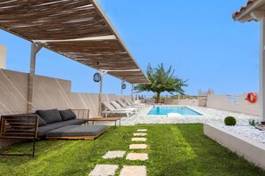 A rooftop pool area with a covered seating area, stone steps leading to the pool, and a view of the cityscape. - Villa Dimitra With Swimming Pool (Rethymno)