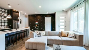 A modern living room with a sectional sofa, ottoman, and a bar area with stools.