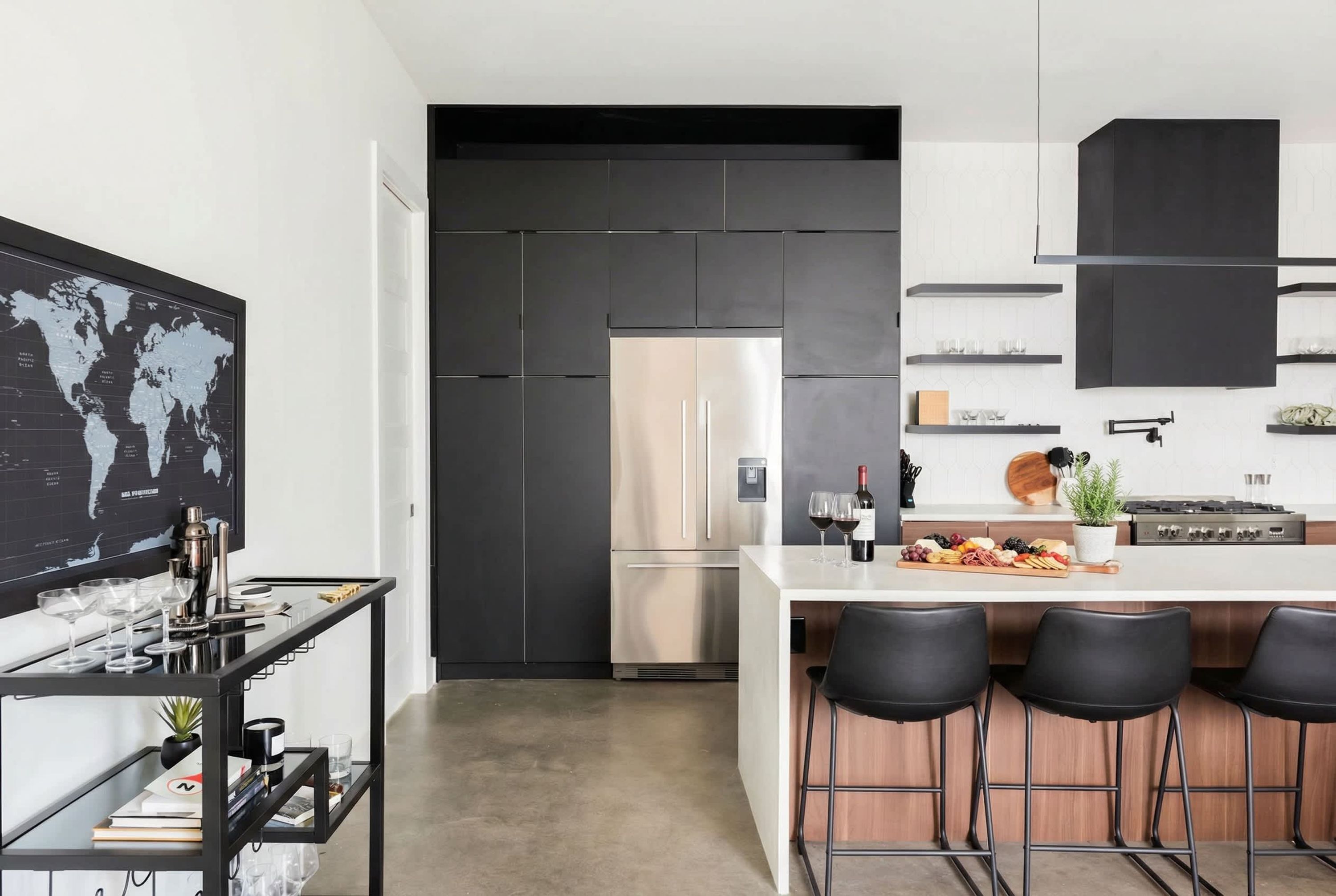 Una cocina moderna con un refrigerador de acero inoxidable, una isla blanca con taburetes de bar y un mapa mundial en la pared.