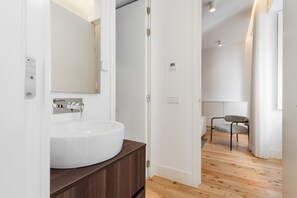 A modern bathroom with a white sink, dark wooden vanity, and a mirror. - Feel Porto Cl Rigos Charm Flat 2 1 (Porto)