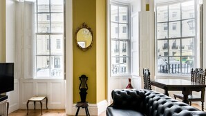 Ein Zimmer mit großem Fenster, Fernseher, Sofa und Tisch.