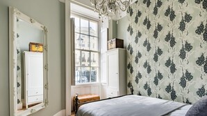 Ein Schlafzimmer mit einem Bett, einem großen Spiegel, einem Fenster und einem Kleiderschrank.