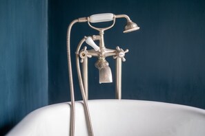 Une baignoire de style rétro, dotée d’un pommeau de douche à main et d’un robinet avec un bec verseur.
