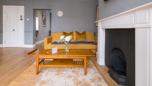 Un salon avec un canapé, une table basse, une cheminée et une horloge au mur.