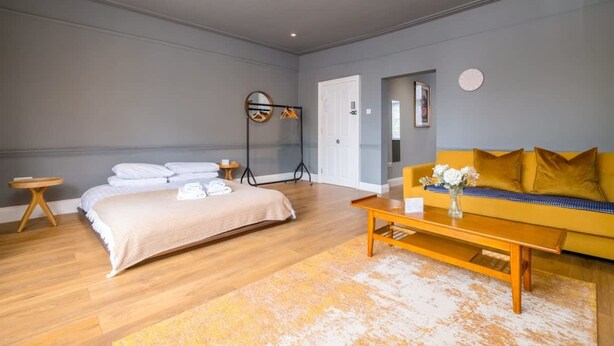 Une chambre à coucher moderne avec un lit, un canapé, une table basse et un miroir.