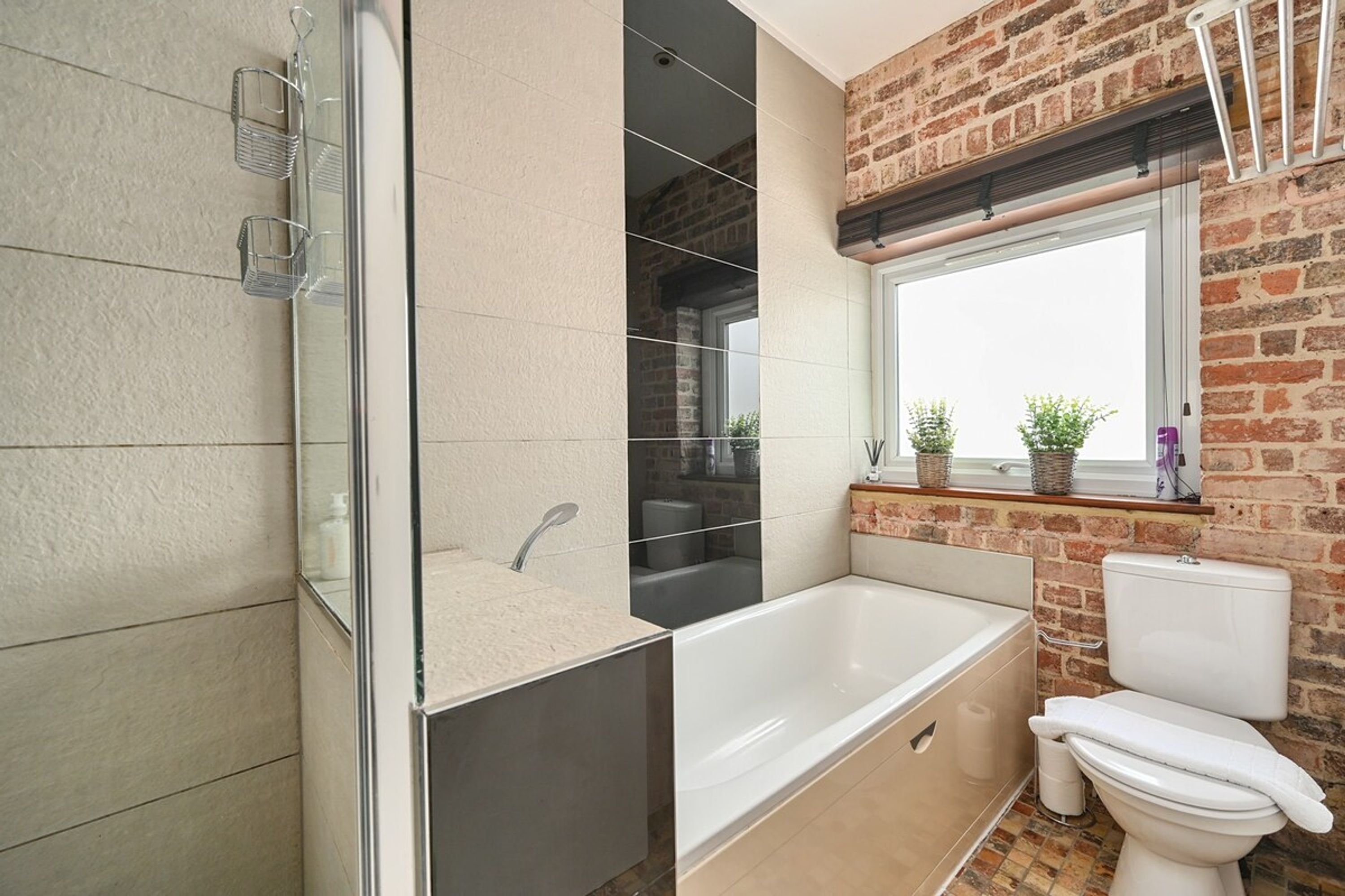 Une salle de bain moderne avec une douche à parois de verre, une baignoire sur pieds et des toilettes.