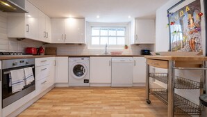 A modern kitchen with white cabinets, a washing machine, a stove, and a sink. - Host Stay George Street Townhouse (Brighton)