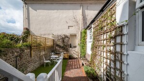 A narrow brick pathway leading to a white building with a wooden fence and climbing plants. - Host Stay George Street Townhouse (Brighton)