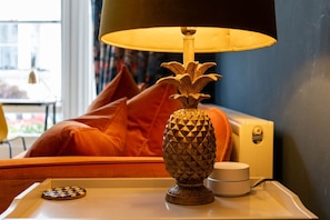 A lamp with a pineapple design on a bedside table, a chessboard, and a cup.