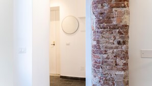 Ein Gang mit einer Ziegel-Säule, einer weißen Tür und einem runden Spiegel an der Wand.