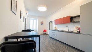 Eine moderne Küche mit grauen Schränken, einem schwarzen Esstisch und einem roten Stuhl.