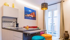 A modern kitchen with a central island, bar stools, and a hanging light fixture. - Golden Shell at Hystorical Center (Naples)