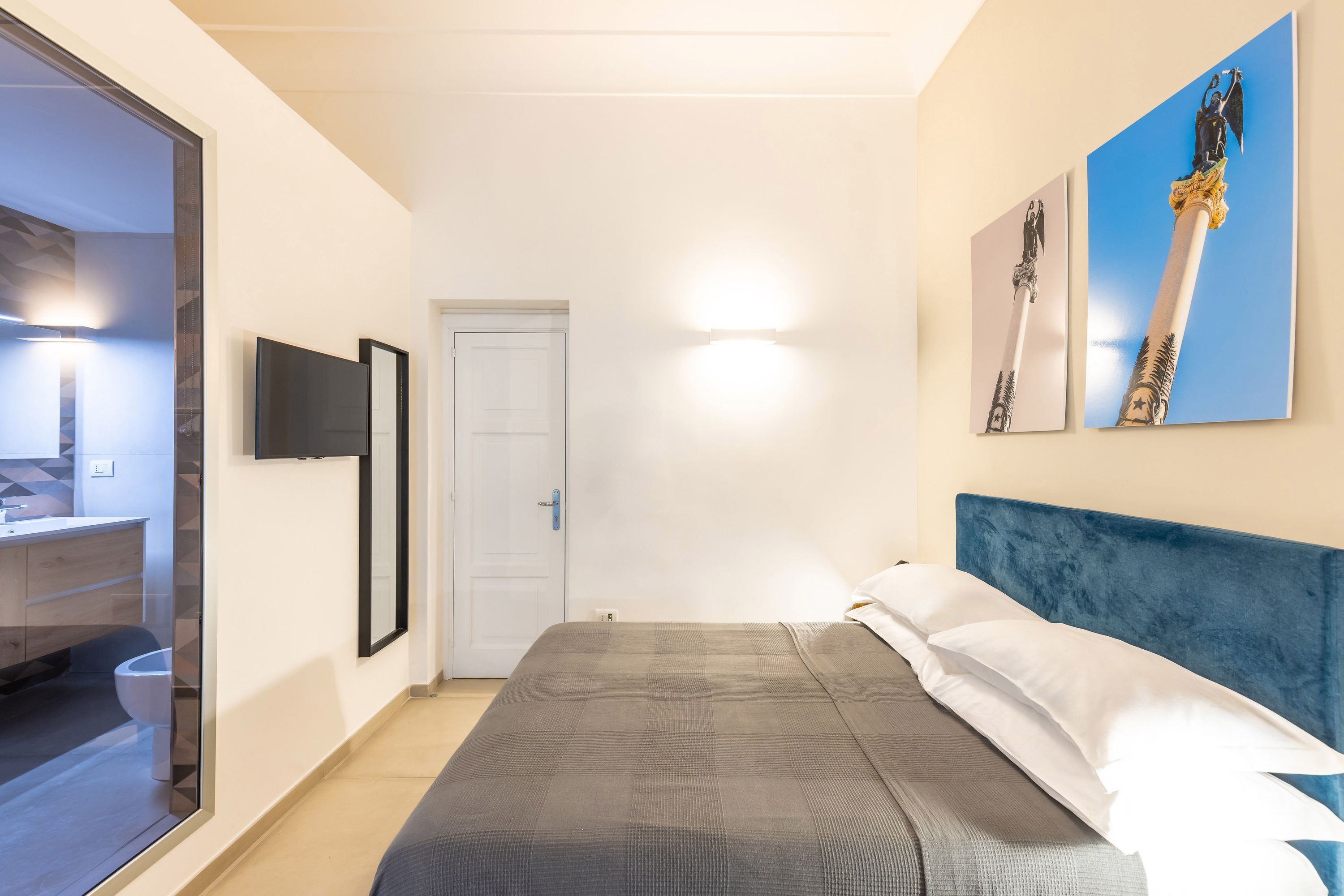 Un dormitorio con una cama, cabecera azul y dos cuadros colgados en la pared.