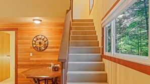 A staircase with carpeted steps leading to a window overlooking greenery. - Lindgren Hause in Enumclaw (Enumclaw)