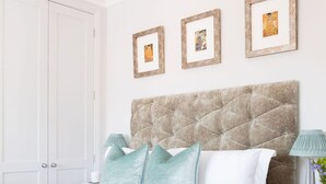 A neatly arranged bedroom with a bed, bedside tables, and framed pictures on the wall.